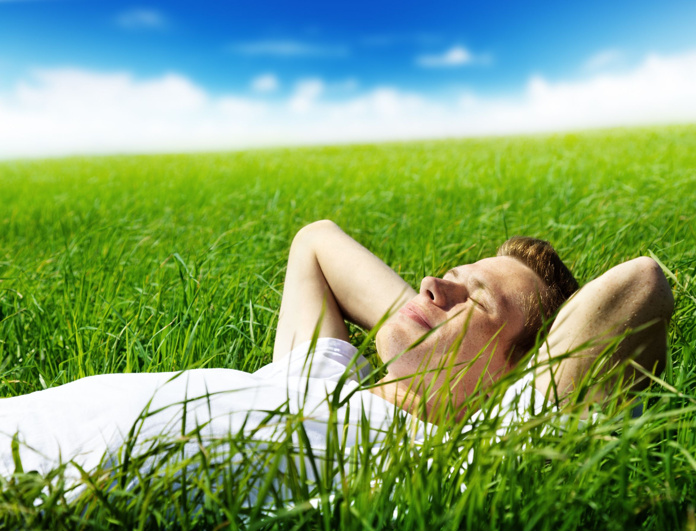 Умиротворенный человек. Расслабление. Человек отдыхает. Лежит на траве. Мужчина лежит на траве.