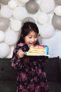 A little girl happy to eat a piece of birthday cake