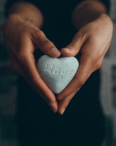 A picture of hands holding a rock with hope written upon it
